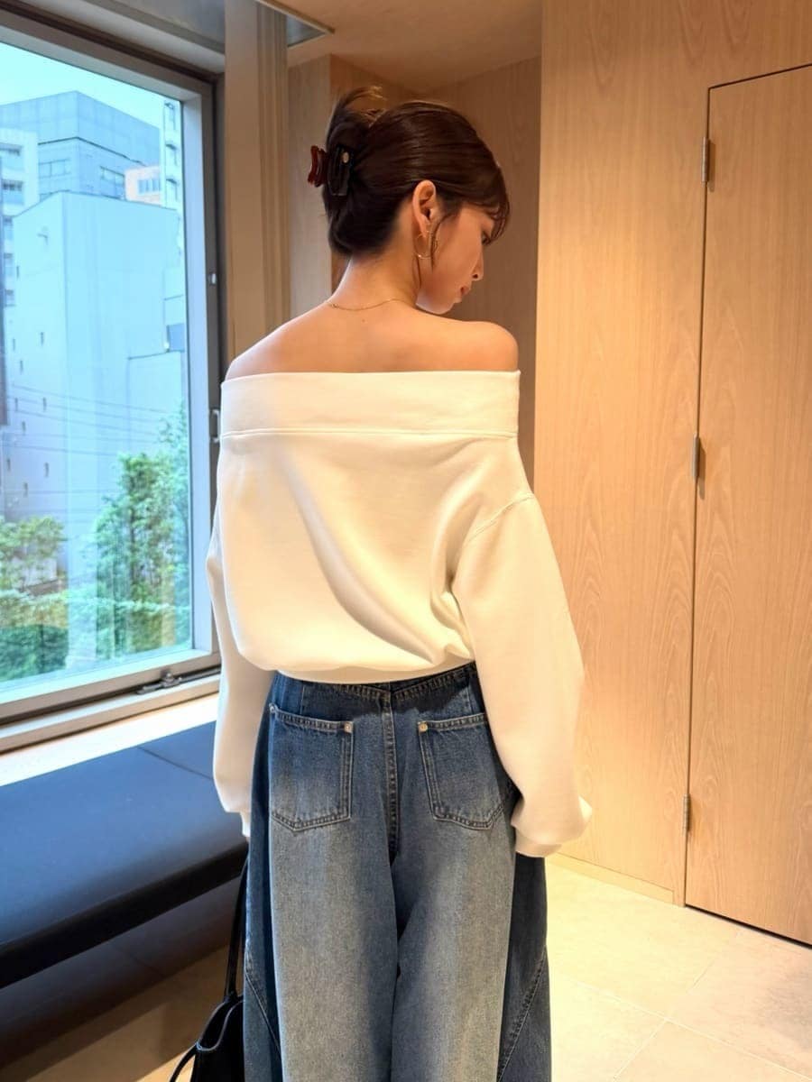 ブルー系のデニムパンツ、ホワイト系のワンピース、ブラック系のボストンバッグを着用したレディースの秋コーディネートの2枚目の写真