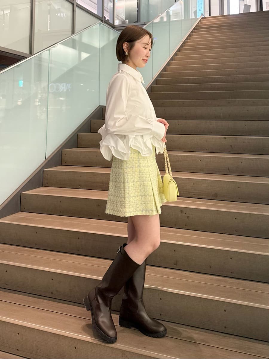 イエロー系のスカート、ホワイト系のシャツ/ブラウス、イエロー系のショルダーバッグを着用したレディースの冬コーディネートの6枚目の写真