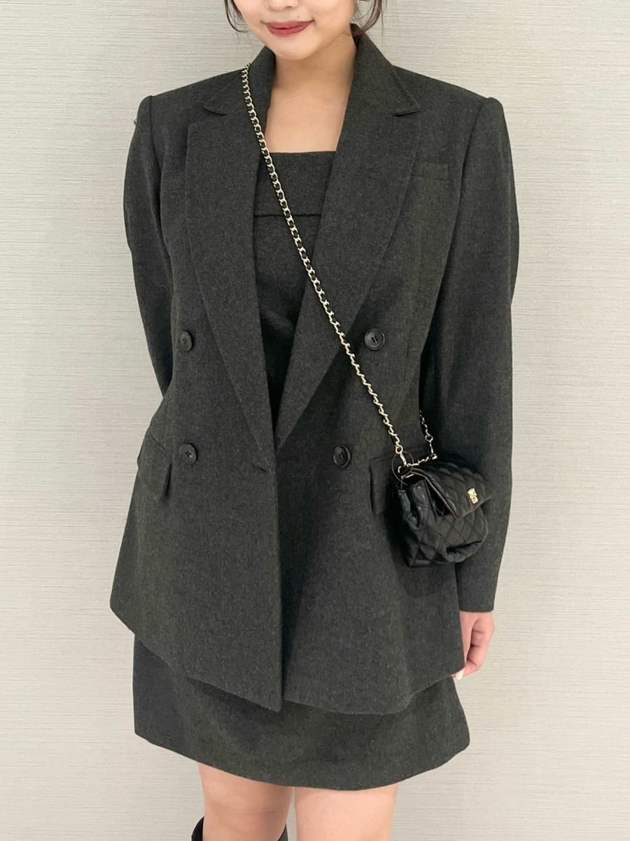 グレー系のテーラードジャケット、グレー系のワンピース、ブラック系のブーツを着用したレディースの秋コーディネートの2枚目の写真