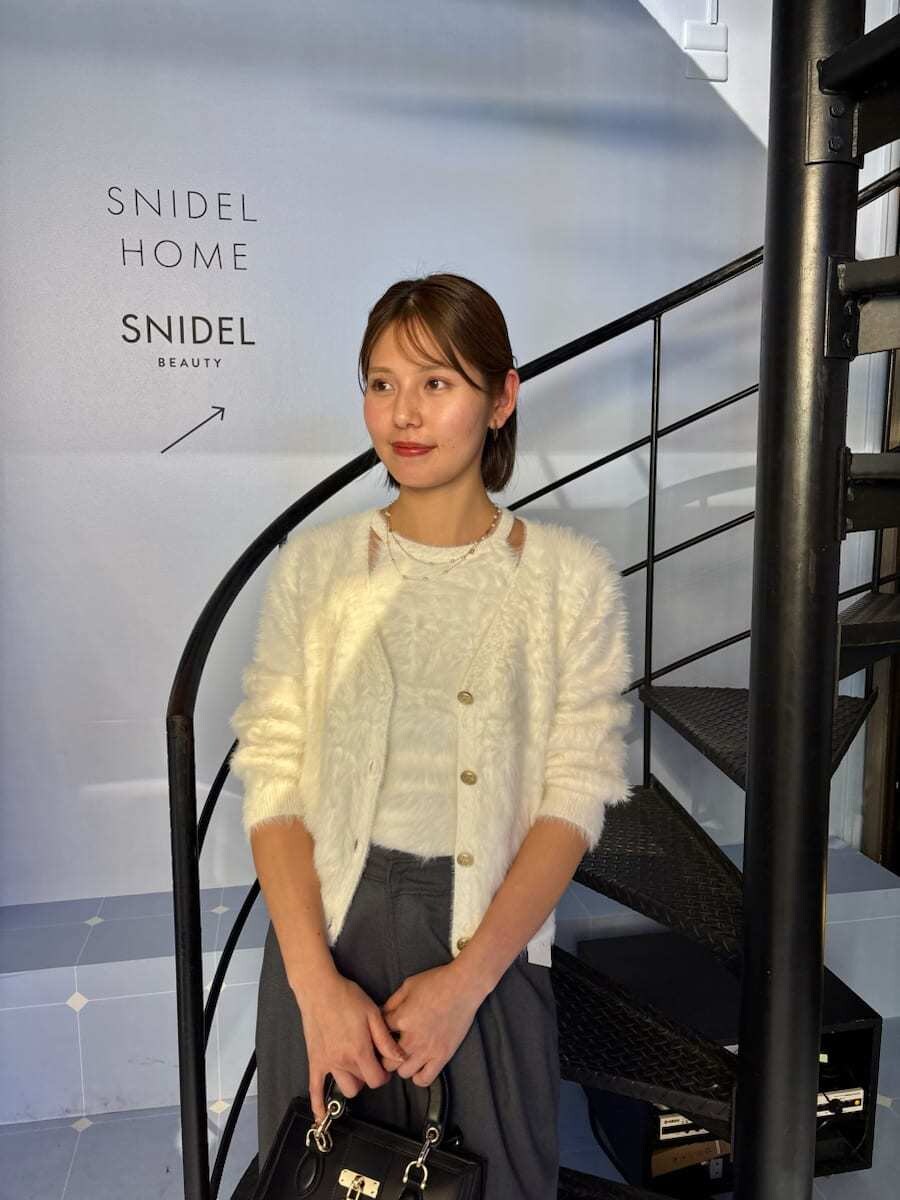 ブラック系のブーツ、ホワイト系のニット/セーター、ブラック系のハンドバッグを着用したレディースの秋コーディネートの5枚目の写真