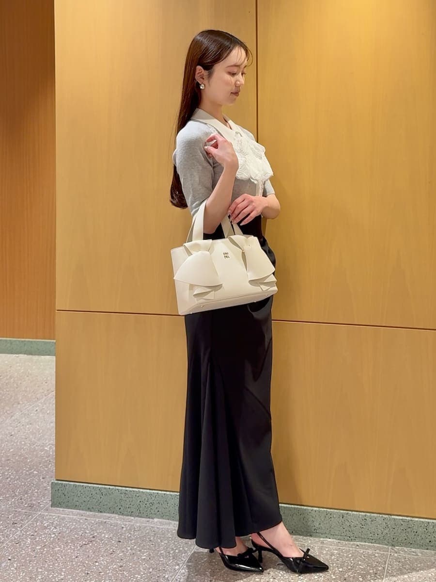 ブラック系のスカート、グレー系のニット/セーター、ホワイト系のハンドバッグを着用したレディースの春コーディネートの2枚目の写真
