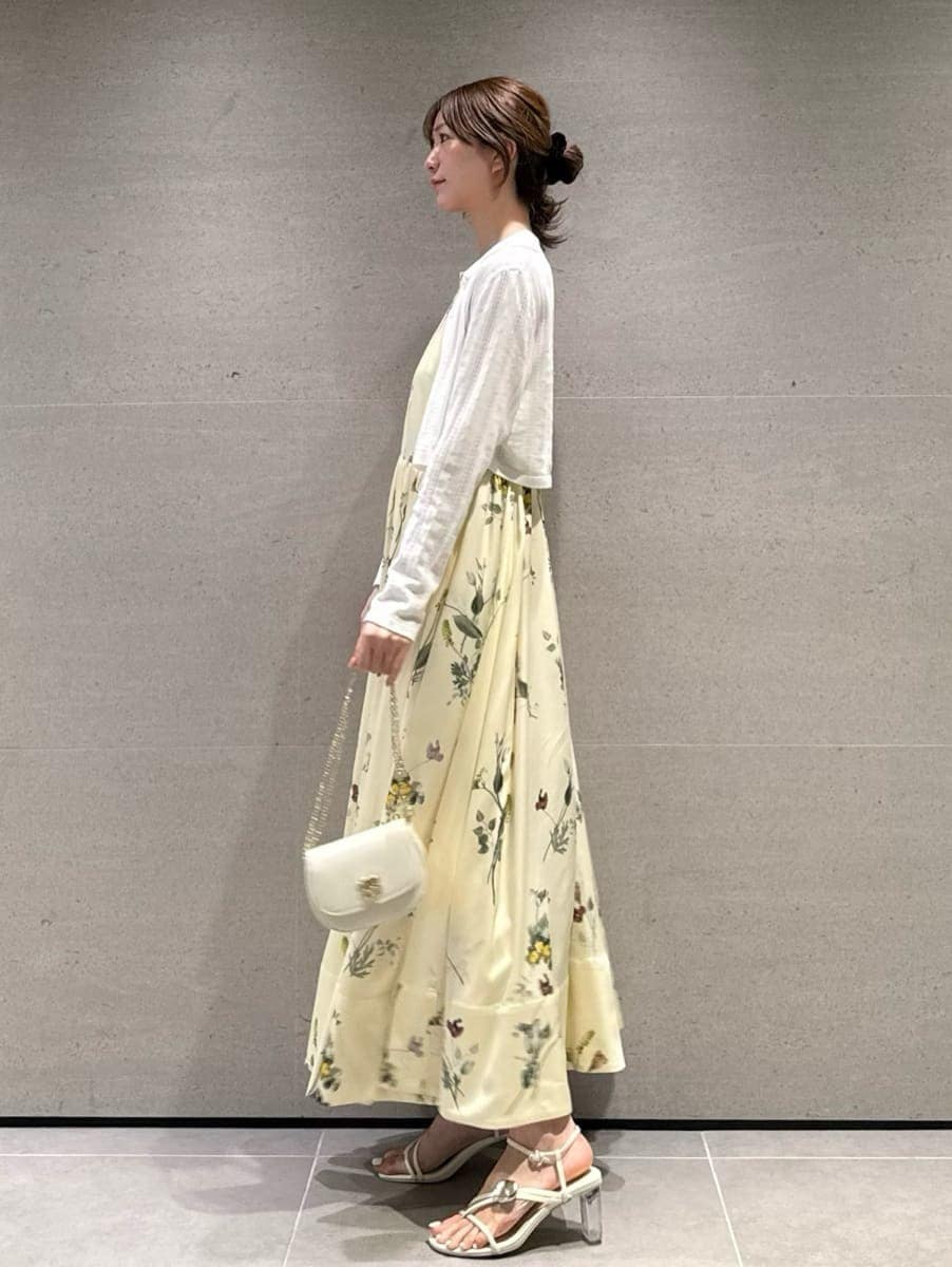 イエロー系のワンピース、ホワイト系のカーディガン/ボレロ、ホワイト系のショルダーバッグを着用したレディースの春コーディネートの2枚目の写真