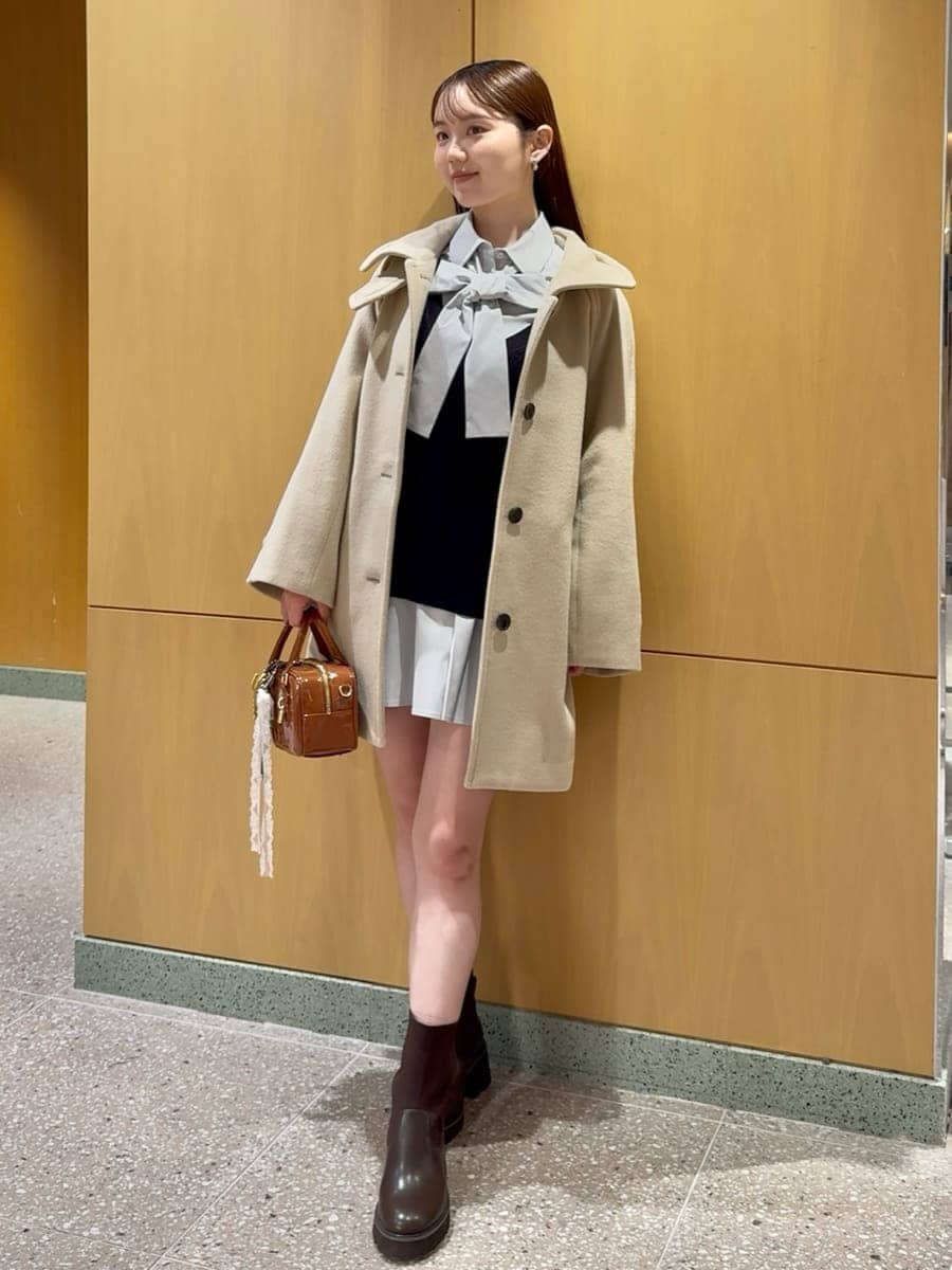 ベージュ系のステンカラーコート、ブルー系のその他トップス、ブラウン系のボストンバッグを着用したレディースの秋コーディネートの4枚目の写真