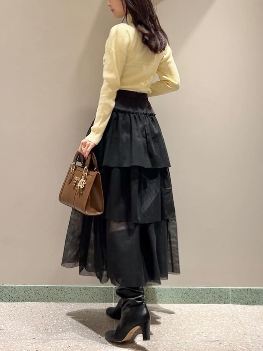 イエロー系のニット/セーター、ホワイト系のムートンコート、ブラック系のスカートを着用したレディースの秋コーディネートの6枚目の写真