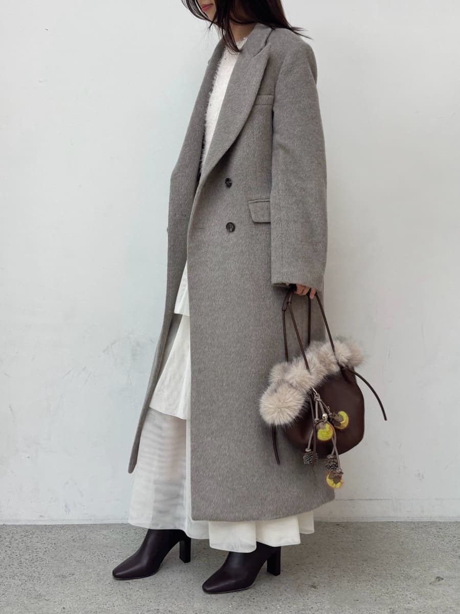 レッド系のブーツ、グレー系のチェスターコート、ホワイト系のスカートを着用したレディースの冬コーディネートの3枚目の写真