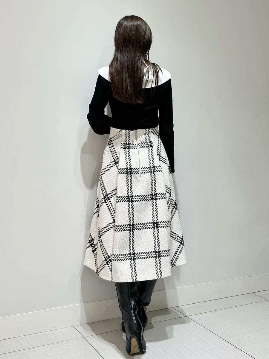 ブラック系のニット/セーター、ホワイト系のスカート、ブラック系のブーツを着用したレディースの秋コーディネートの4枚目の写真