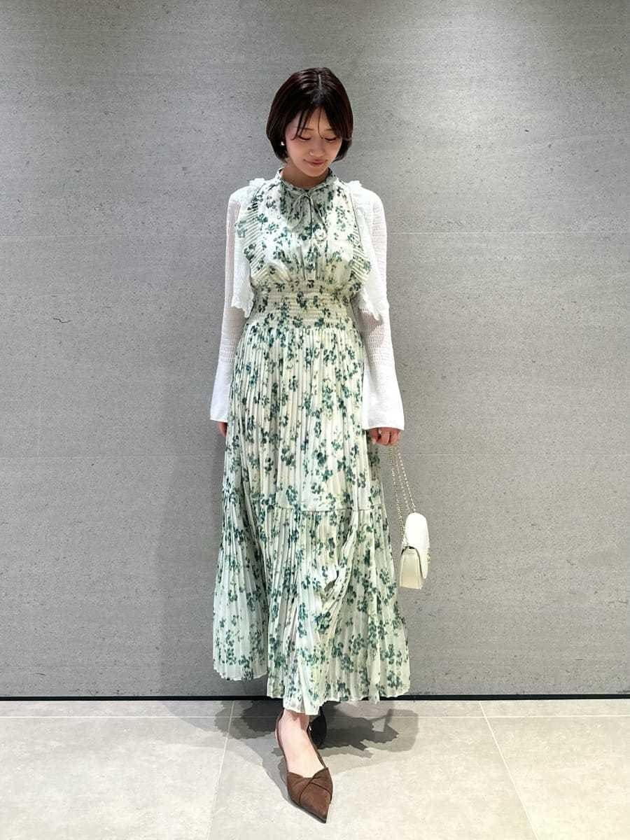 グリーン系のワンピース、ホワイト系のカーディガン/ボレロ、ブラウン系のパンプスを着用したレディースの冬コーディネートの2枚目の写真