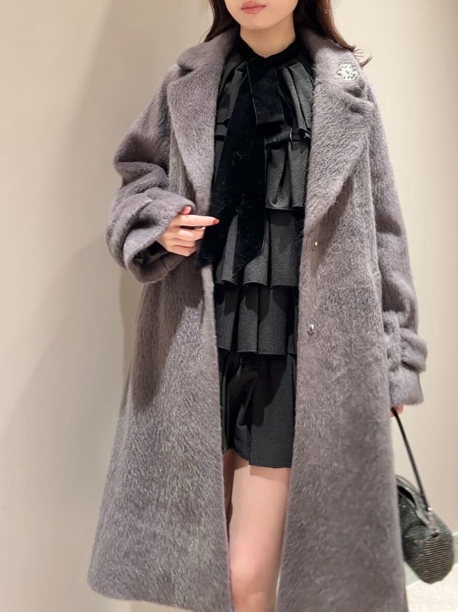 グレー系のブーツ、グレー系のチェスターコート、ブラック系のドレスを着用したレディースの冬コーディネートの4枚目の写真