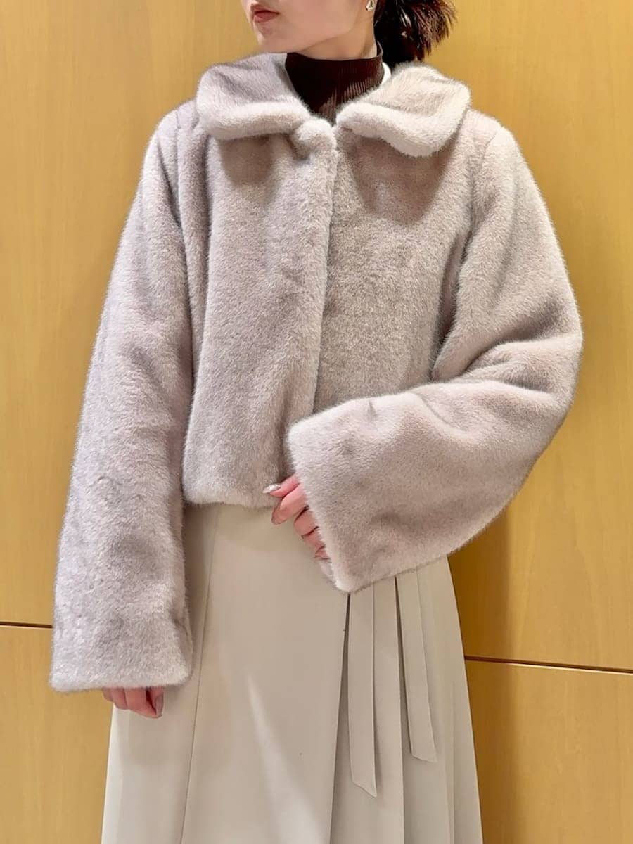 ピンク系のステンカラーコート、ベージュ系のワンピース、ブラウン系のニット/セーターを着用したレディースの秋コーディネートの5枚目の写真