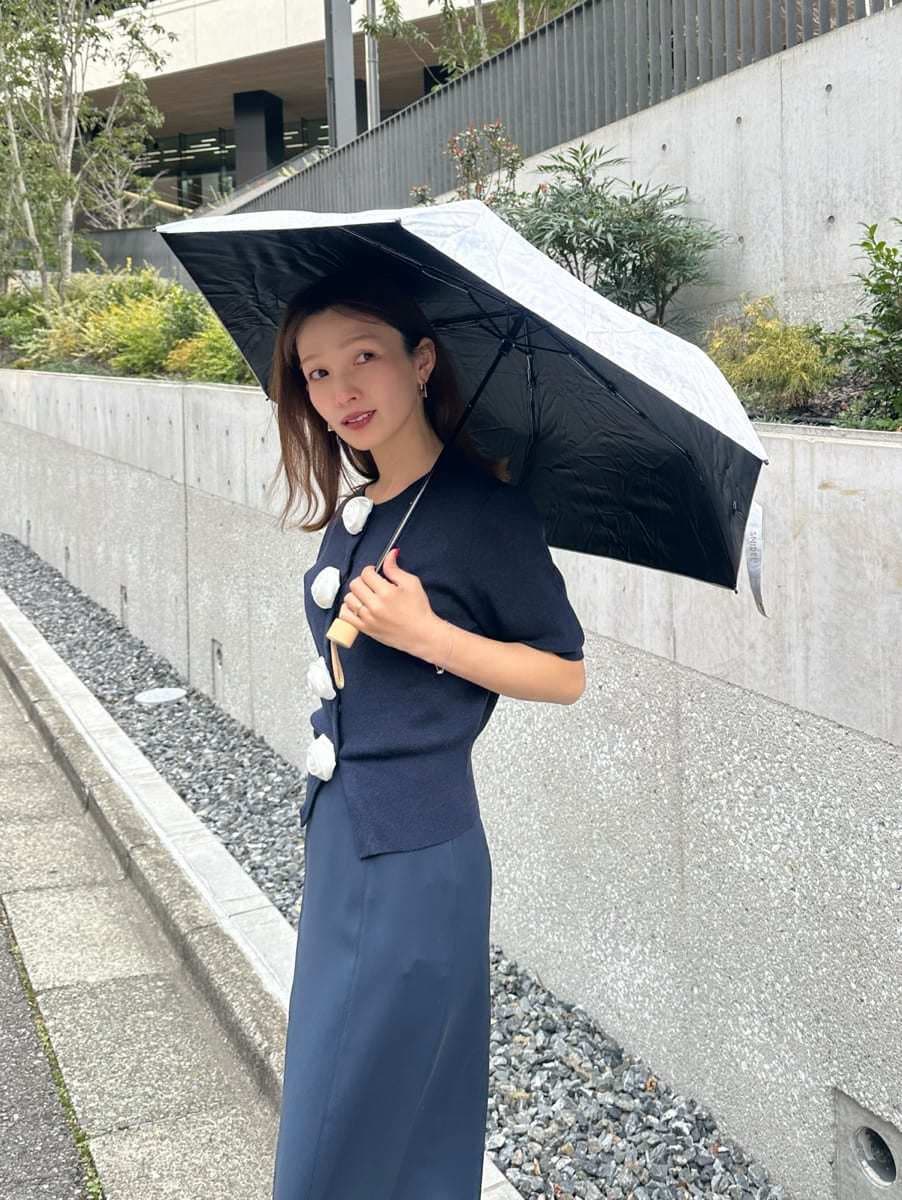 ブルー系のスカート、ブルー系のカーディガン/ボレロ、ピンク系の折りたたみ傘を着用したレディースの春コーディネートの3枚目の写真