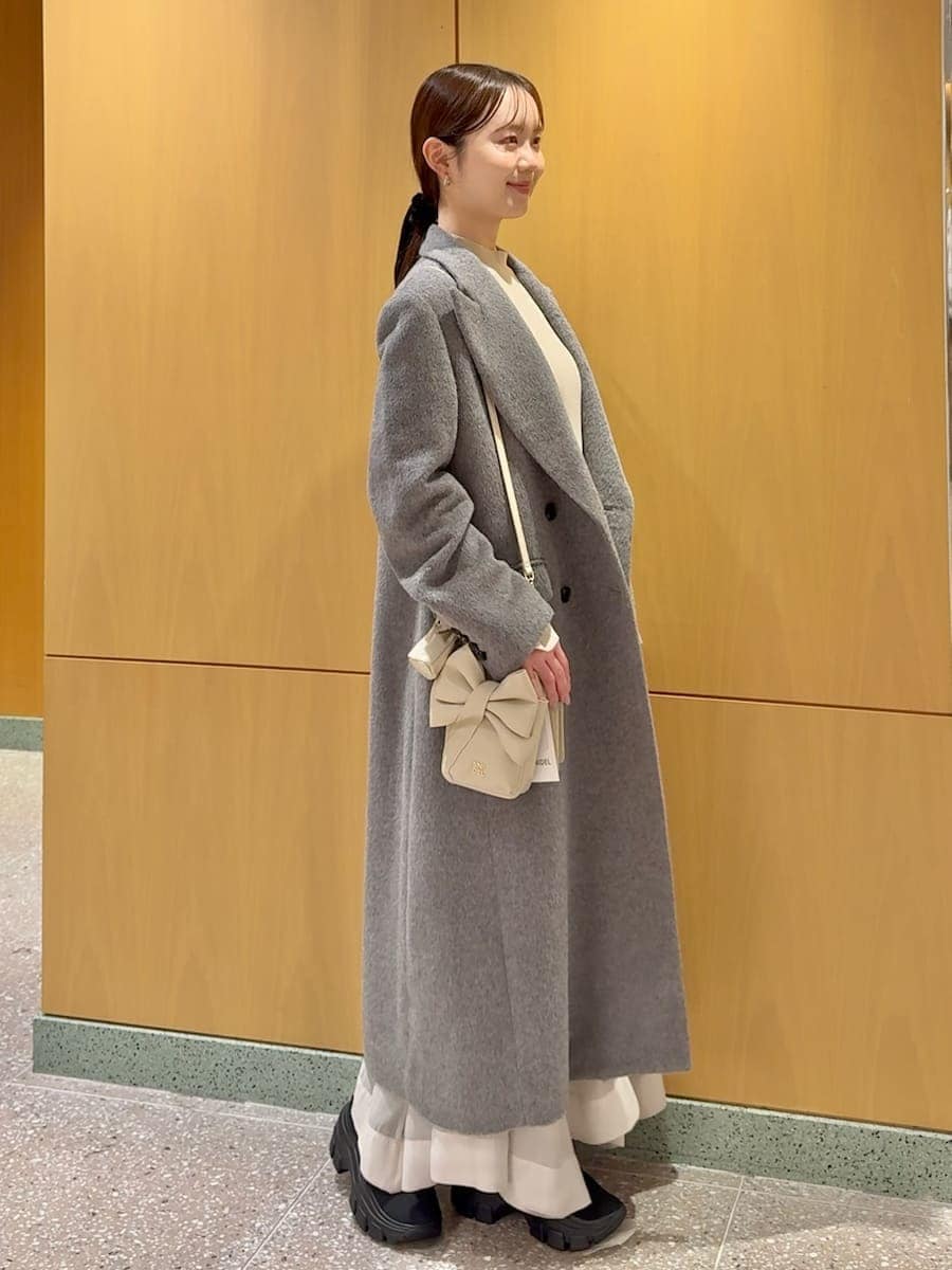 グレー系のチェスターコート、ホワイト系のワンピース、ブラック系のブーツを着用したレディースの冬コーディネートの3枚目の写真