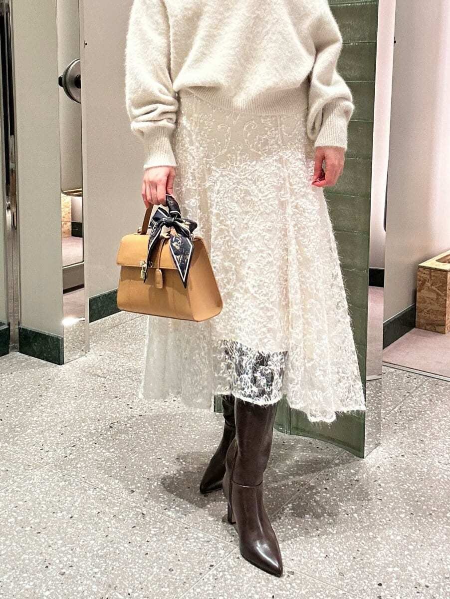 ホワイト系のニット/セーター、ホワイト系のスカート、グレー系のブーツを着用したレディースの秋コーディネートの3枚目の写真