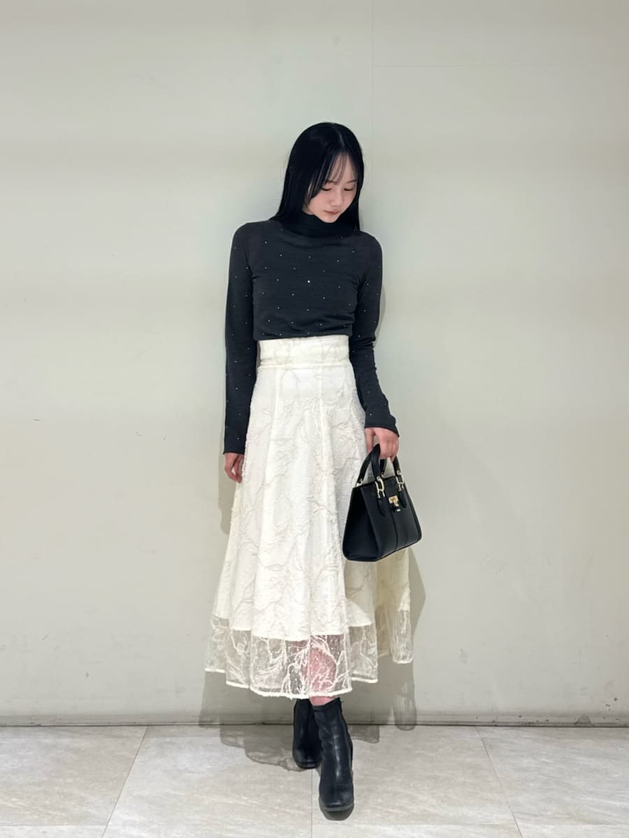 ホワイト系のスカート、グレー系のニット/セーター、ブラック系のハンドバッグを着用したレディースの秋コーディネートの2枚目の写真