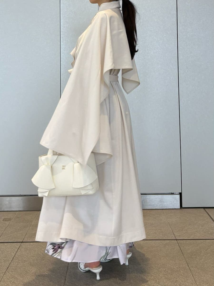 ホワイト系のトレンチコート、パープル系のワンピース、その他のパンプスを着用したレディースの冬コーディネートの9枚目の写真