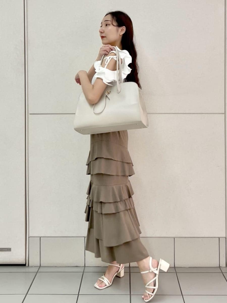ベージュ系のスカート、ホワイト系のニット/セーター、ホワイト系のトートバッグを着用したレディースの夏コーディネートの3枚目の写真