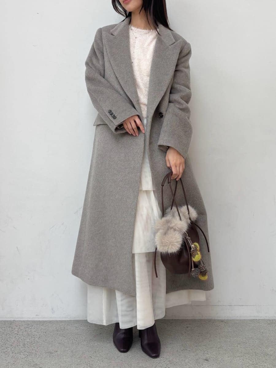 レッド系のブーツ、グレー系のチェスターコート、ホワイト系のスカートを着用したレディースの冬コーディネートの2枚目の写真
