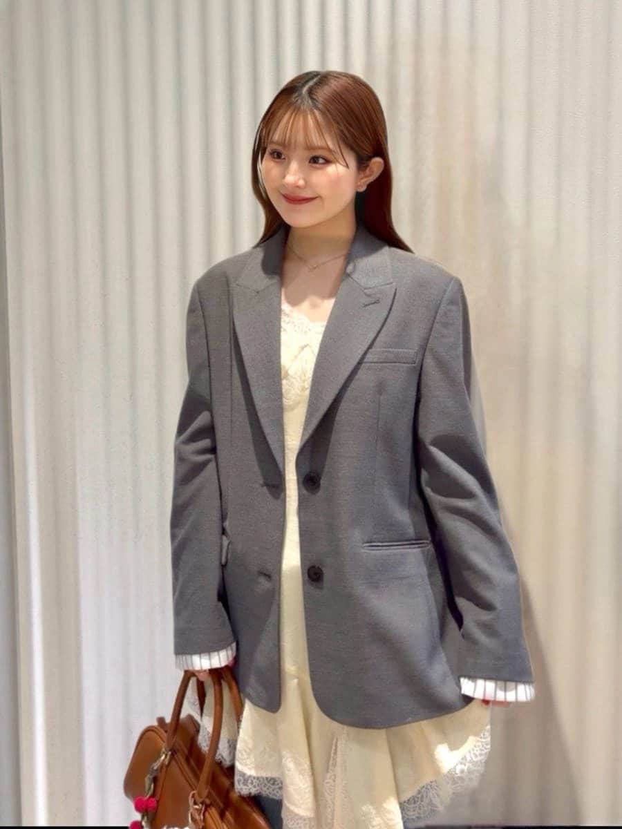 グレー系のテーラードジャケット、ブルー系のデニムパンツ、イエロー系のキャミソールを着用したレディースの春コーディネートの4枚目の写真