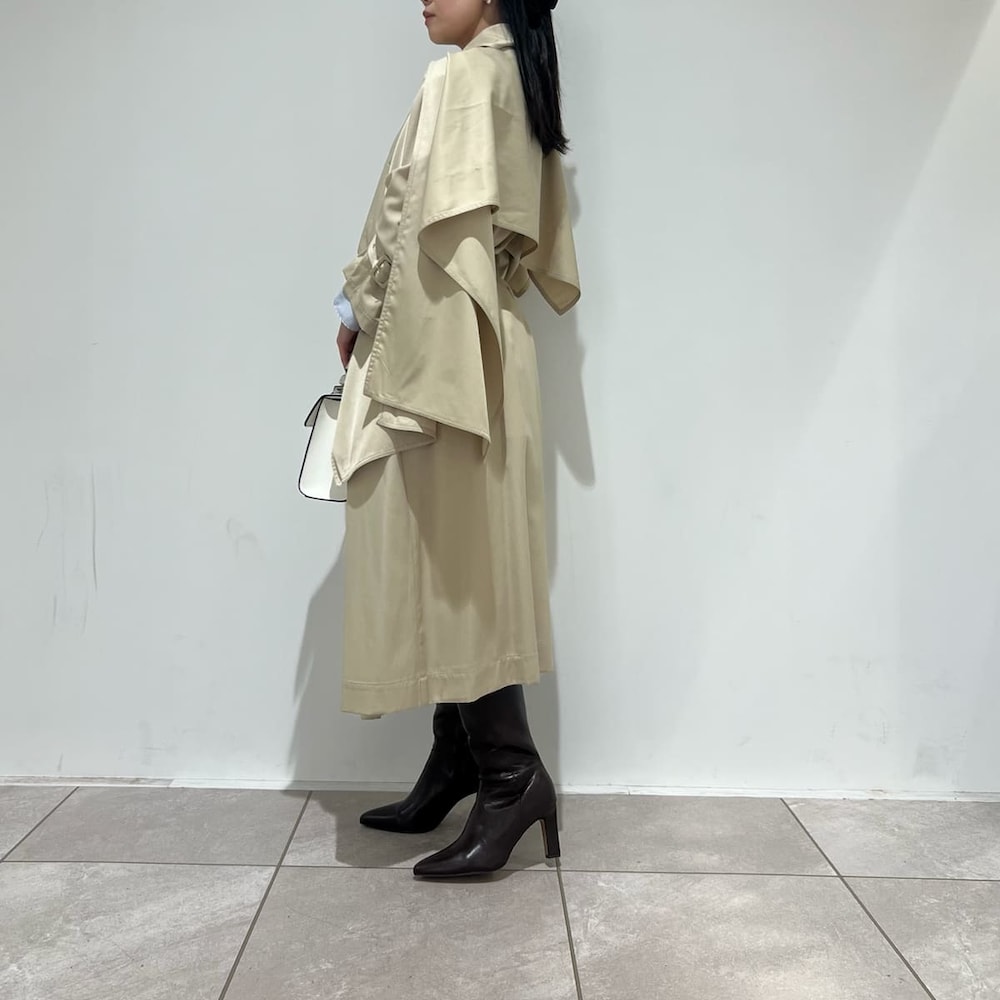 ブラウン系のブーツ、ベージュ系のトレンチコート、ホワイト系のハンドバッグを着用したレディースの冬コーディネートの2枚目の写真