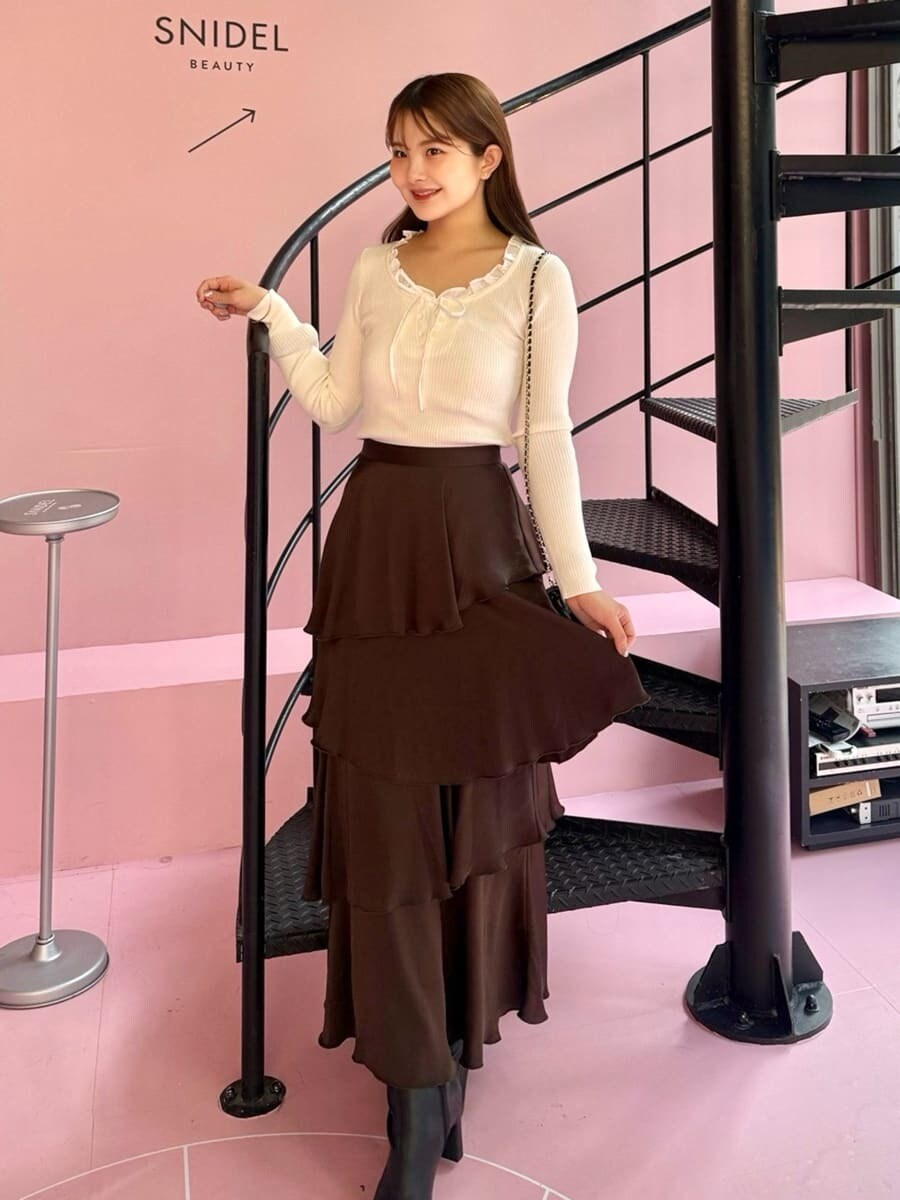 ホワイト系のニット/セーター、ブラウン系のスカート、ブラック系のブーツを着用したレディースの秋コーディネートの7枚目の写真