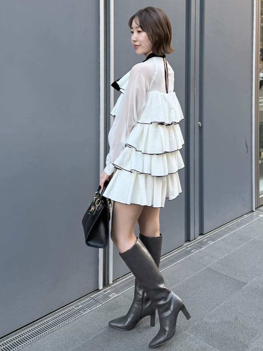 ホワイト系のドレス、ブラック系のハンドバッグを着用したレディースの冬コーディネートの7枚目の写真