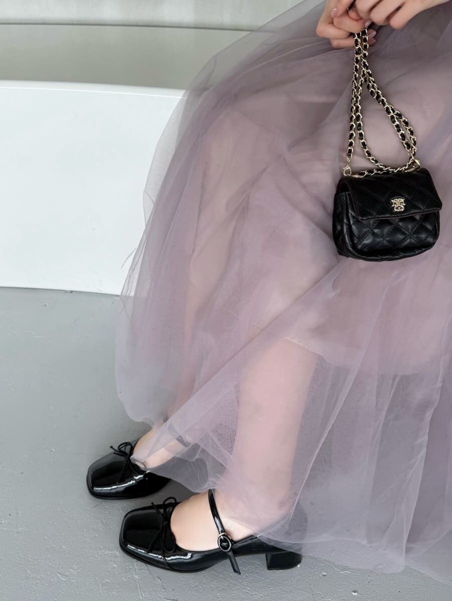 ブラック系のショルダーバッグ、ブラック系のパンプス、その他のイヤリングを着用したレディースの夏コーディネートの6枚目の写真