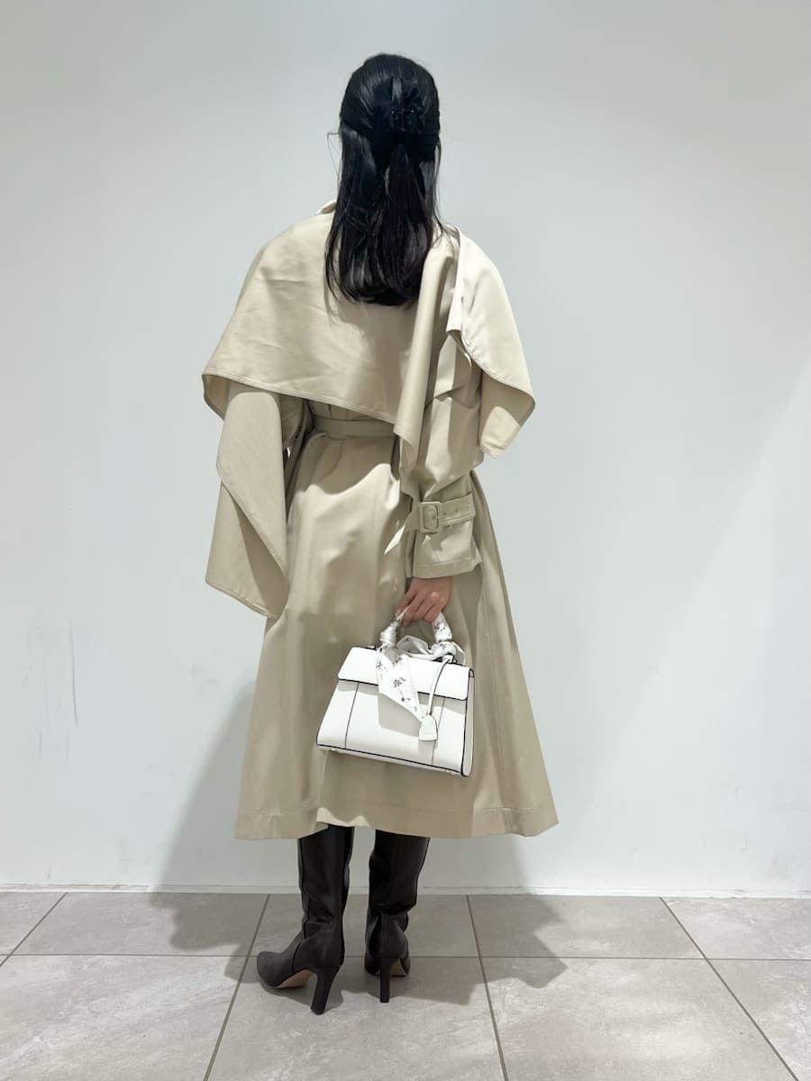 ブラウン系のブーツ、ベージュ系のトレンチコート、ホワイト系のハンドバッグを着用したレディースの冬コーディネートの4枚目の写真