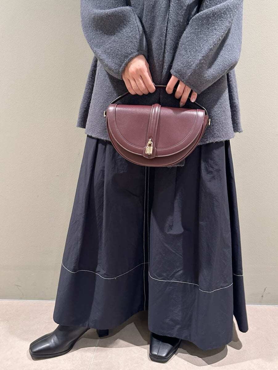 ブラック系のワンピース、ブラウン系のハンドバッグ、ブラック系のブーツを着用したレディースの秋コーディネートの4枚目の写真