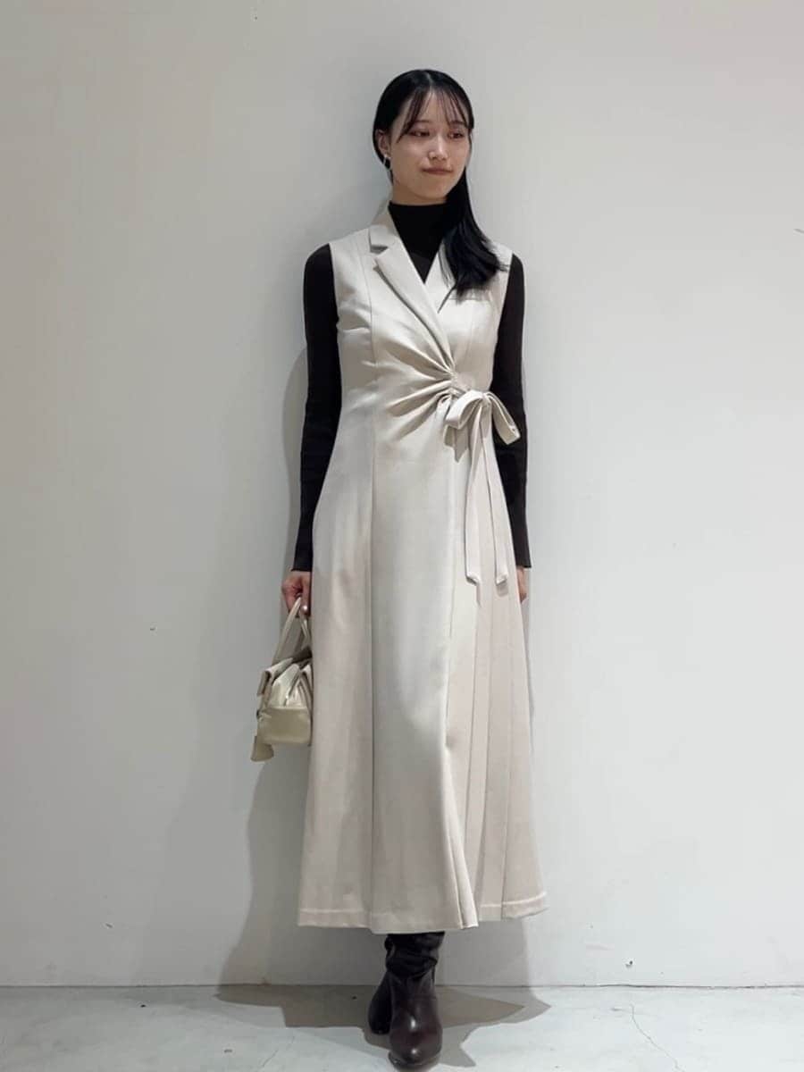 ブラウン系のステンカラーコート、ベージュ系のワンピース、ブラウン系のニット/セーターを着用したレディースの秋コーディネートの5枚目の写真