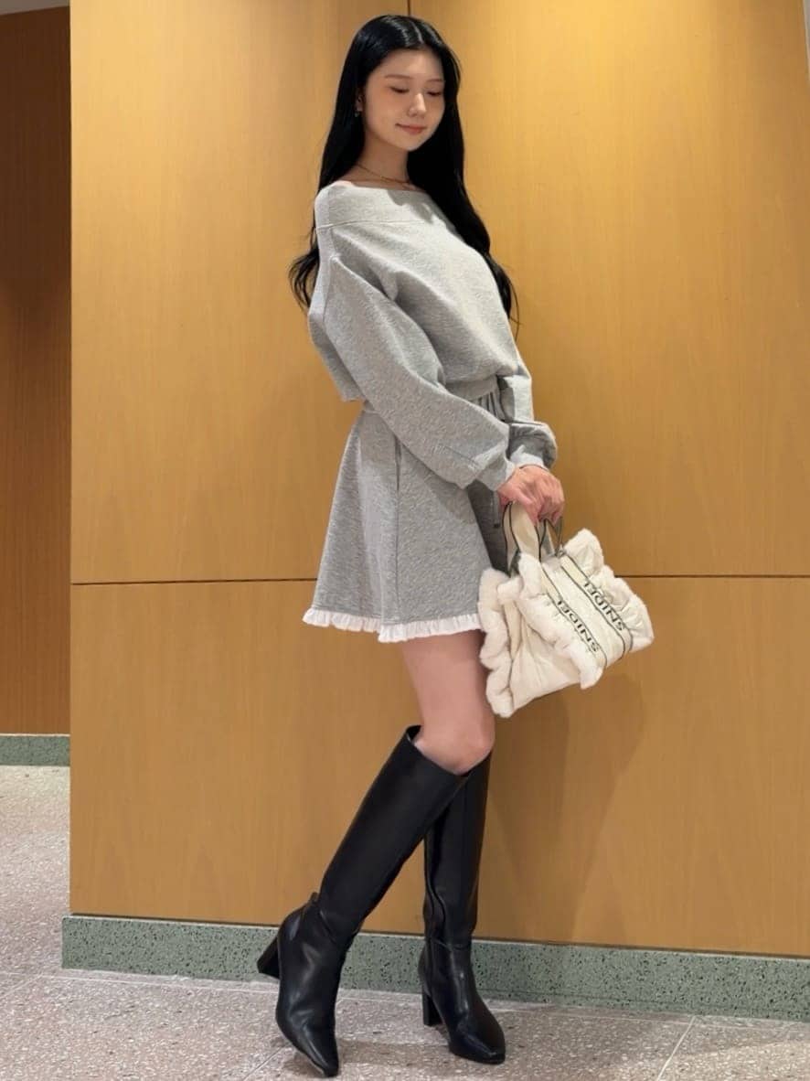 グレー系のワンピース、ブラック系のブーツ、ホワイト系のショルダーバッグを着用したレディースの秋コーディネートの3枚目の写真