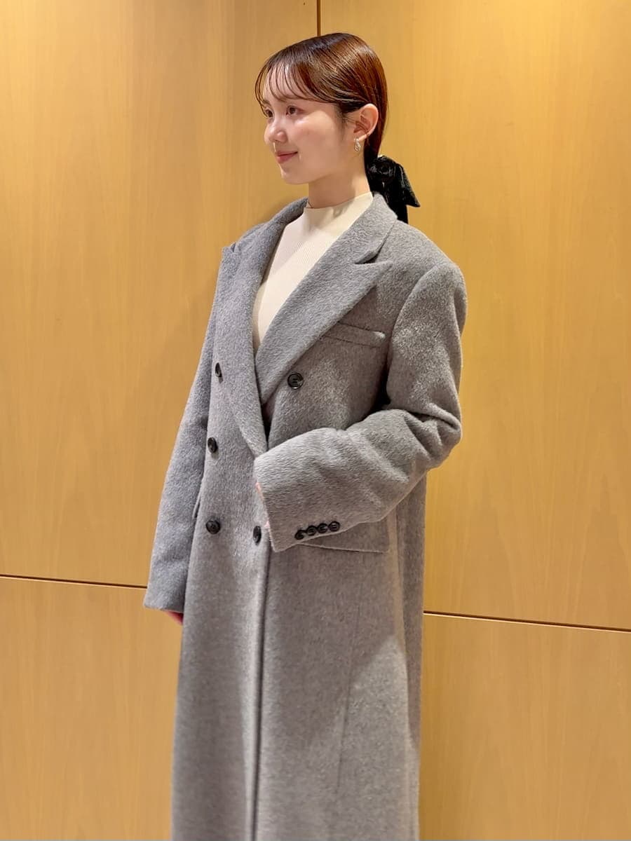 グレー系のチェスターコート、ホワイト系のワンピース、ブラック系のブーツを着用したレディースの冬コーディネートの7枚目の写真