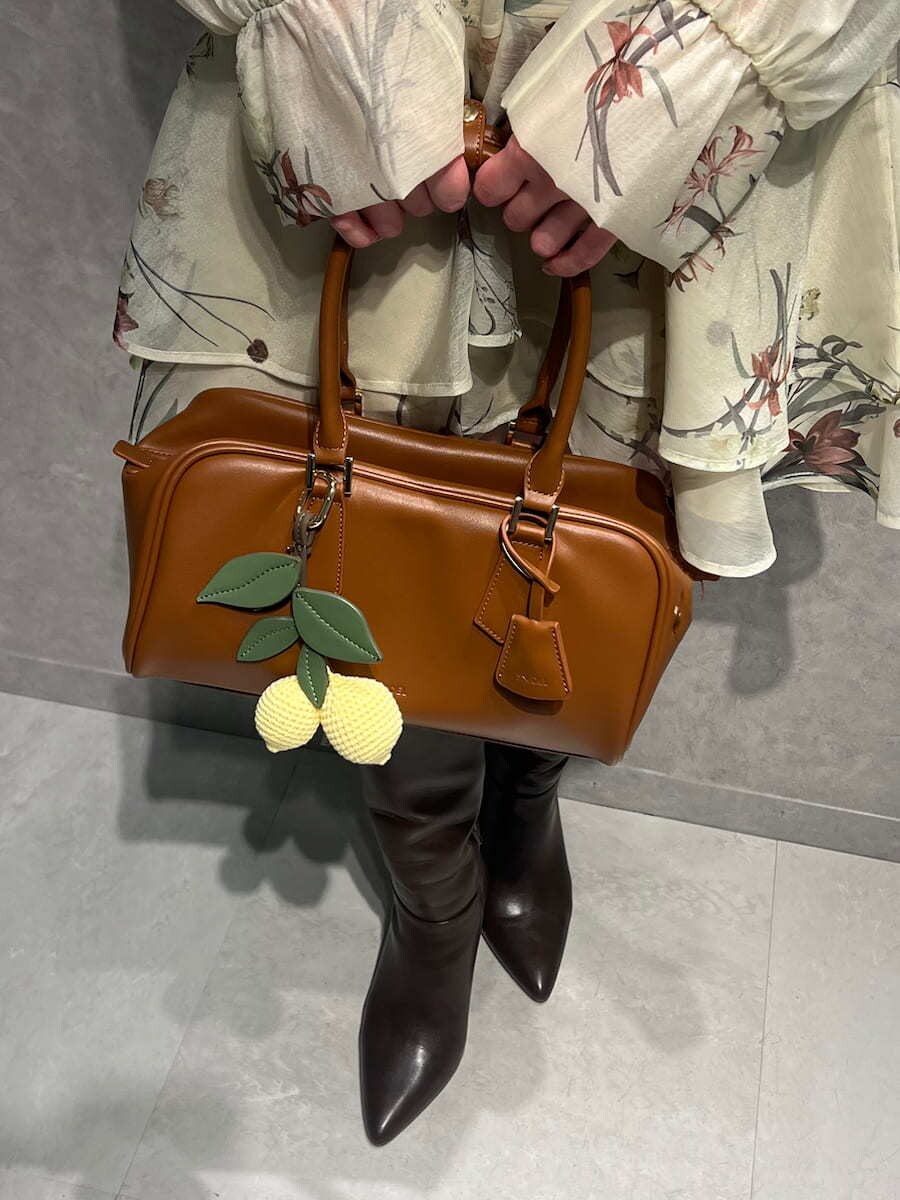 ブラウン系のブーツ、イエロー系のワンピース、イエロー系のボストンバッグを着用したレディースの冬コーディネートの4枚目の写真