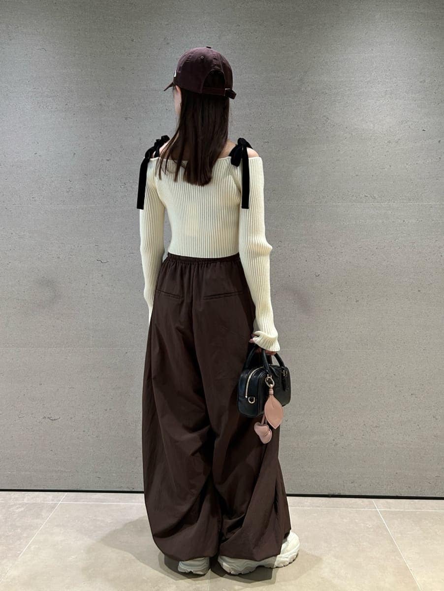 ホワイト系のニット/セーター、ブラウン系のその他パンツ、ブラック系のボストンバッグを着用したレディースの夏コーディネートの5枚目の写真