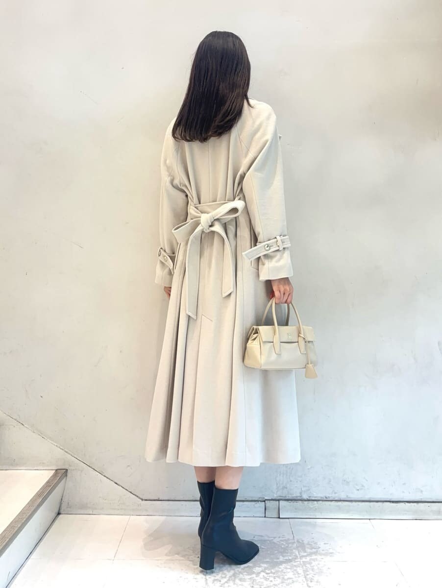 ホワイト系のチェスターコート、ベージュ系のワンピース、ホワイト系のボストンバッグを着用したレディースの秋コーディネートの4枚目の写真