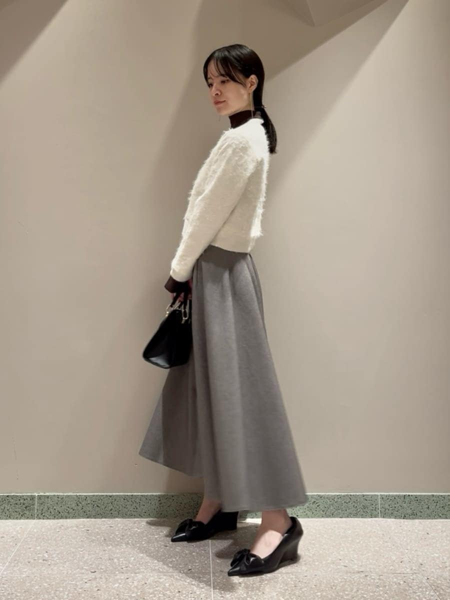 グレー系のスカート、ブラウン系のニット/セーター、ホワイト系のカーディガン/ボレロを着用したレディースの冬コーディネートの2枚目の写真
