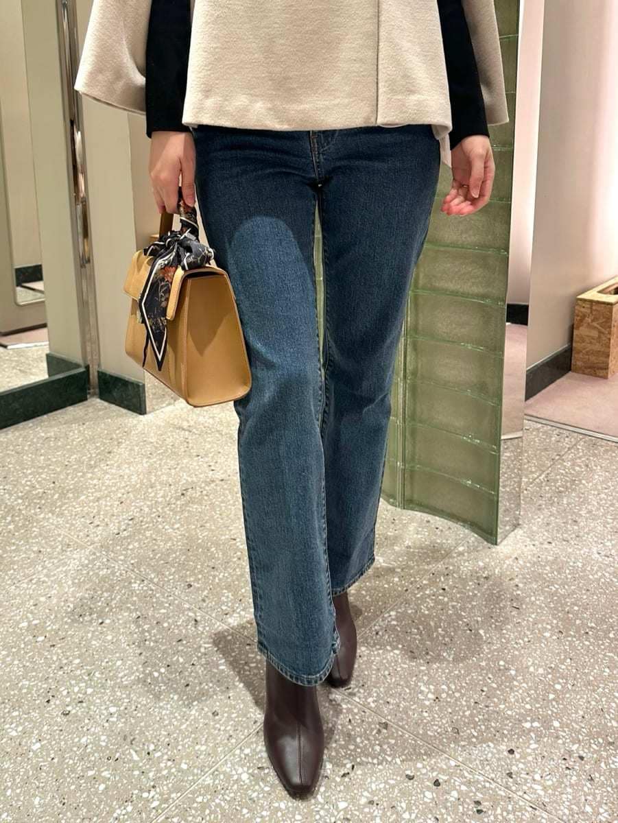 ホワイト系のチェスターコート、ブルー系のデニムパンツを着用したレディースの秋コーディネートの3枚目の写真