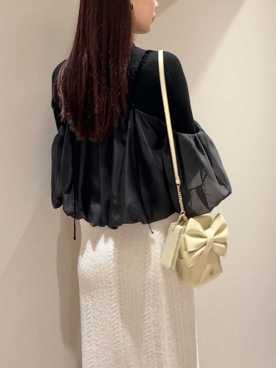 ホワイト系のスカート、ブラック系のニット/セーター、イエロー系のショルダーバッグを着用したレディースの秋コーディネートの4枚目の写真