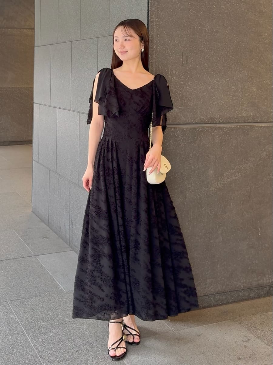 ブラック系のワンピース、ホワイト系のショルダーバッグ、ホワイト系の折りたたみ傘を着用したレディースの春コーディネートの3枚目の写真