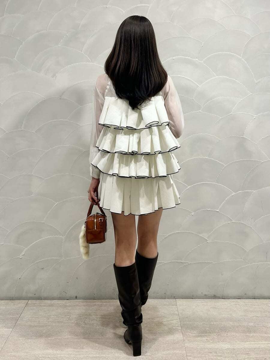 ブラウン系のボストンバッグ、ホワイト系のドレス、イエロー系のキーケース/キーアクセサリーを着用したレディースの冬コーディネートの3枚目の写真