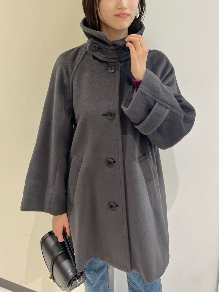 グレー系のステンカラーコート、レッド系のニット/セーター、ブルー系のデニムパンツを着用したレディースの秋コーディネートの7枚目の写真