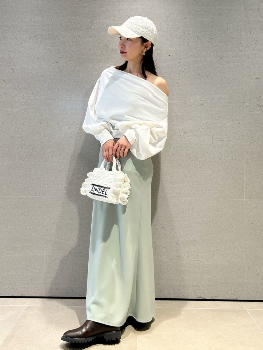 グリーン系のスカート、ホワイト系のスウェット、ホワイト系のショルダーバッグを着用したレディースの春コーディネートの2枚目の写真