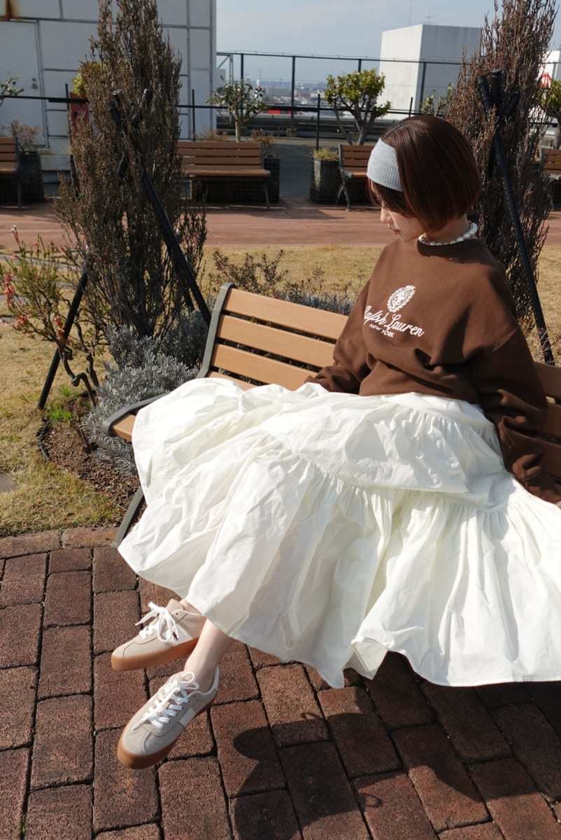 ホワイト系のスカート、ブラウン系のスウェット、ベージュ系のスニーカーを着用したレディースの春コーディネートの7枚目の写真