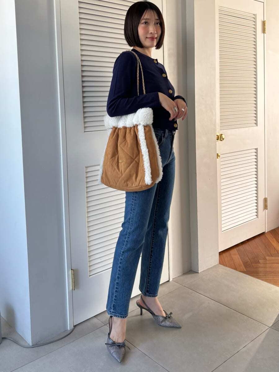 ブルー系のデニムパンツ、ブラウン系のハンドバッグを着用したレディースの秋コーディネートの5枚目の写真