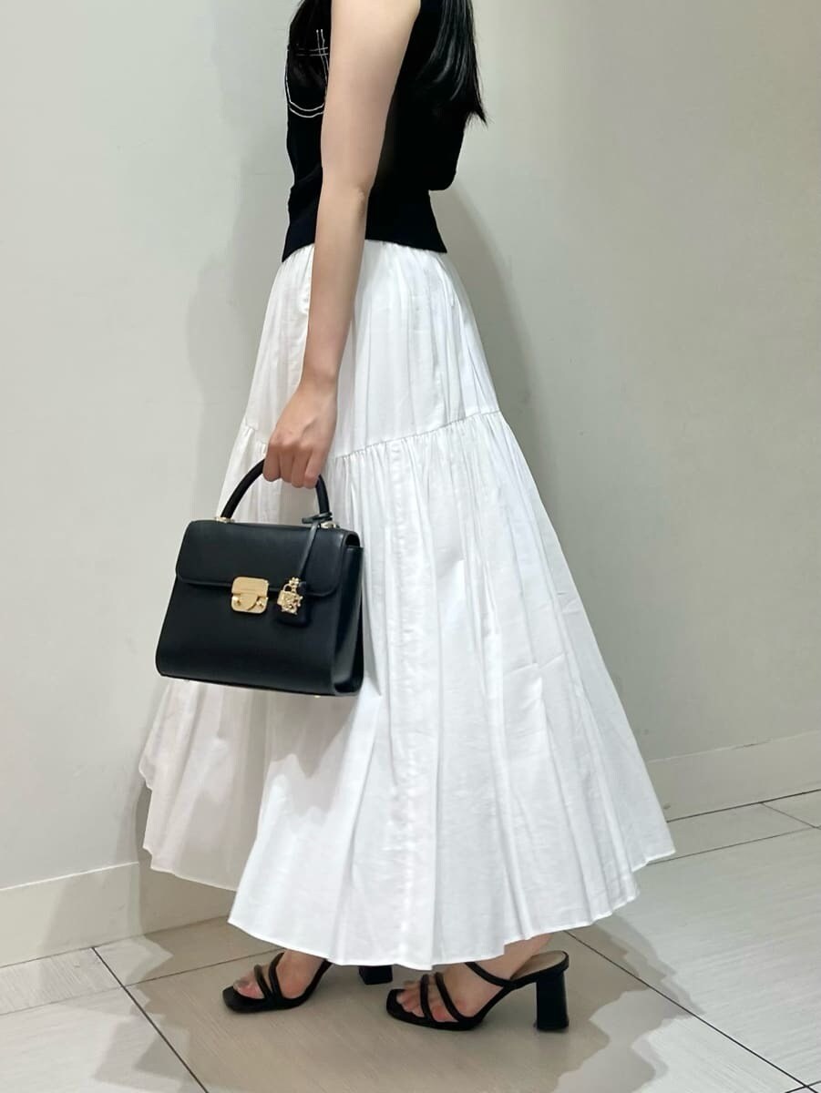 ブルー系のニット/セーター、ホワイト系のスカート、ブラック系のショルダーバッグを着用したレディースの夏コーディネートの4枚目の写真