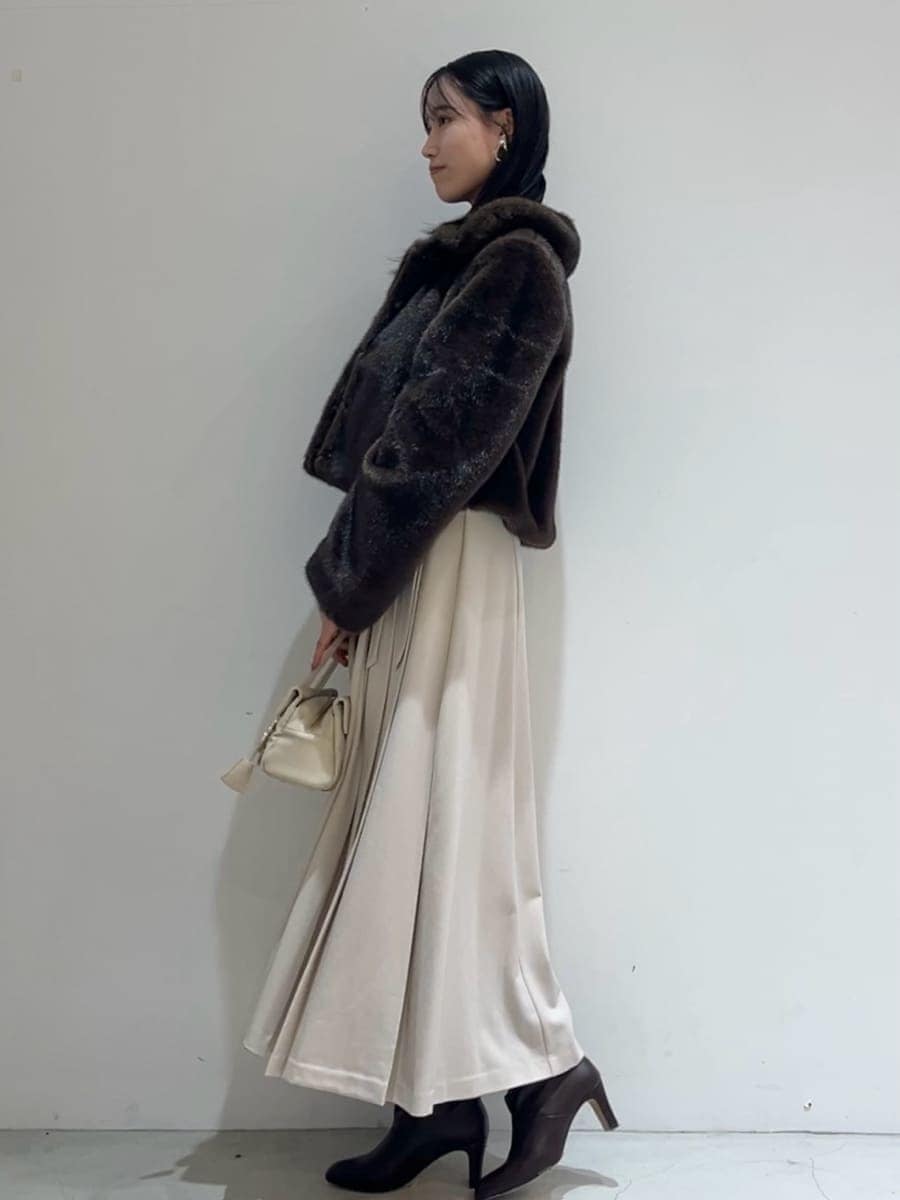 ブラウン系のステンカラーコート、ベージュ系のワンピース、ブラウン系のニット/セーターを着用したレディースの秋コーディネートの3枚目の写真