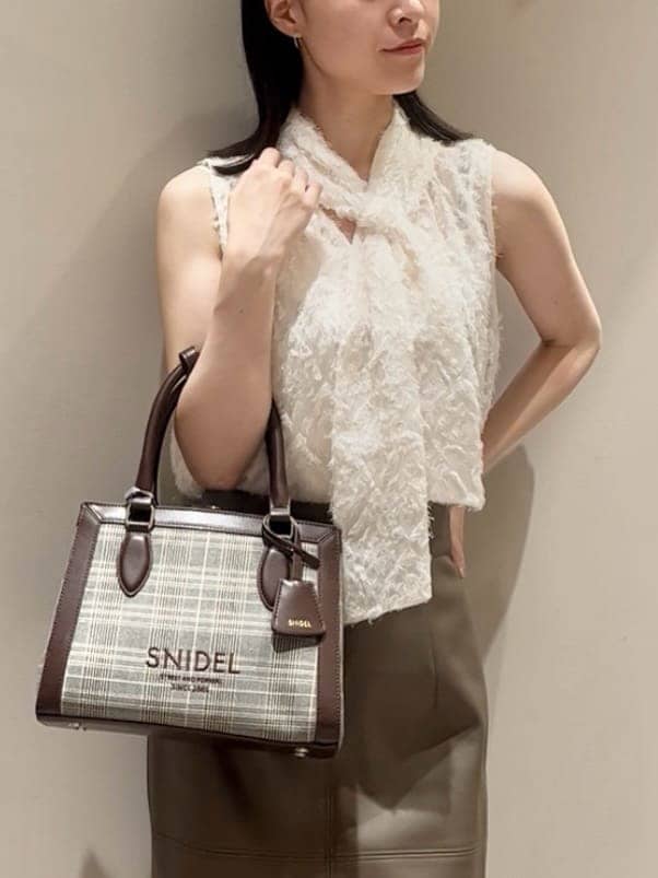 ホワイト系のシャツ/ブラウス、ブラウン系のスカート、ブラウン系のハンドバッグを着用したレディースの夏コーディネートの5枚目の写真