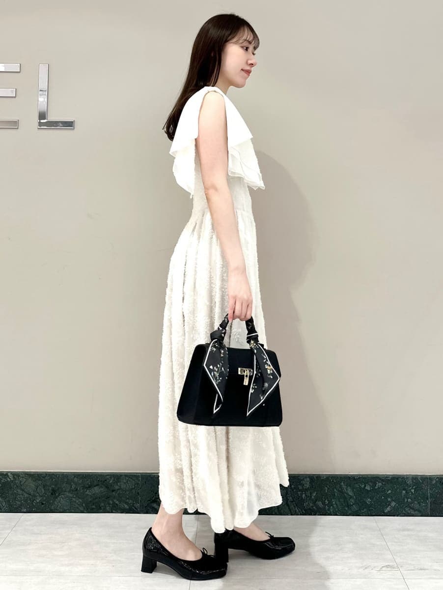 ホワイト系のワンピース、ブラック系のハンドバッグ、ブラック系のパンプスを着用したレディースの春コーディネートの3枚目の写真