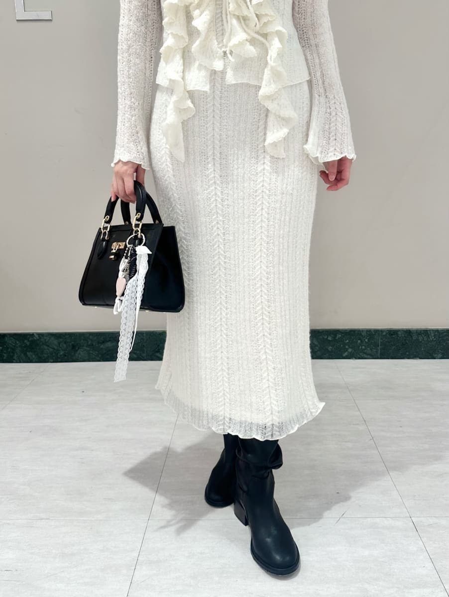 ホワイト系のスカート、ホワイト系のニット/セーター、ブラック系のハンドバッグを着用したレディースの秋コーディネートの3枚目の写真