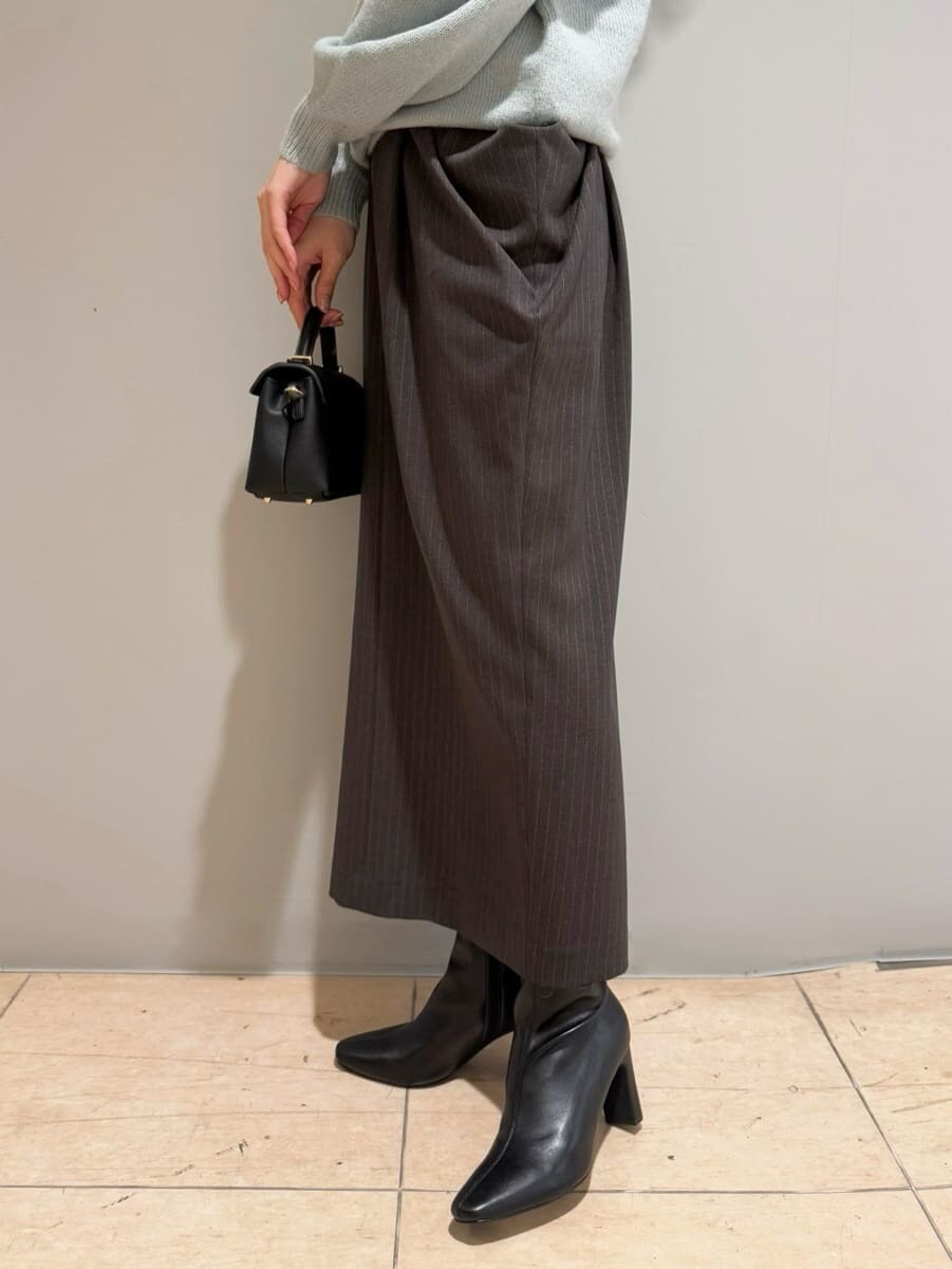 グリーン系のニット/セーター、グレー系のスカート、ブラック系のショルダーバッグを着用したレディースの秋コーディネートの5枚目の写真