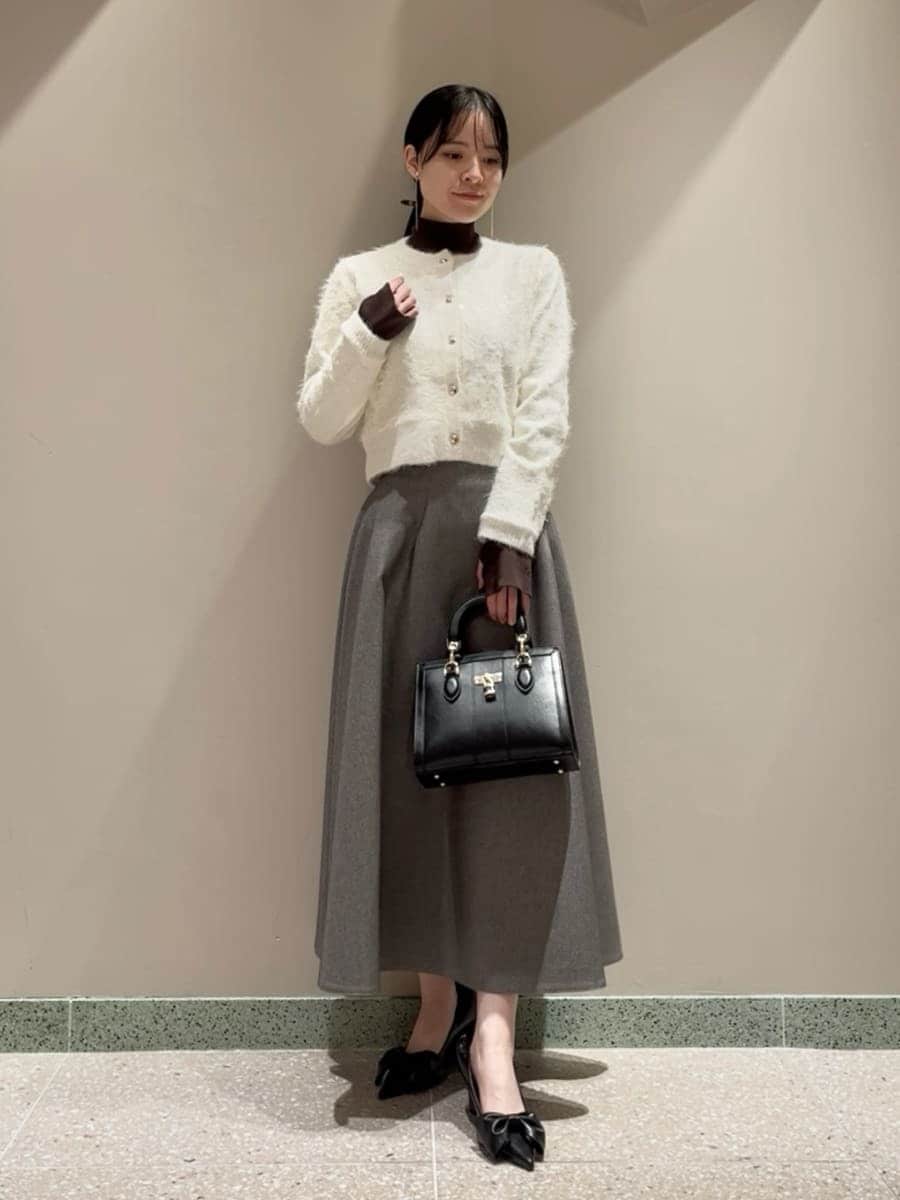 グレー系のスカート、ブラウン系のニット/セーター、ホワイト系のカーディガン/ボレロを着用したレディースの冬コーディネートの4枚目の写真