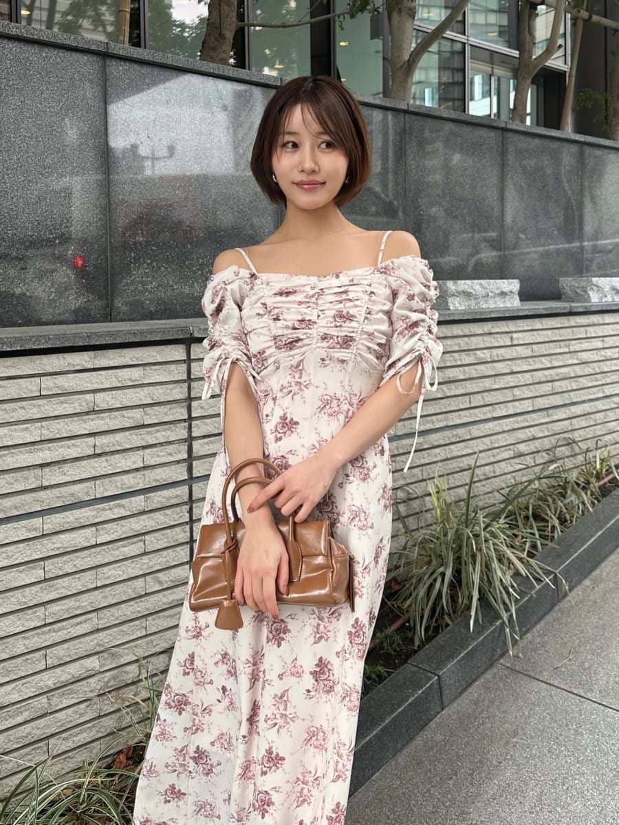 イエロー系のボストンバッグ、ピンク系のワンピースを着用したレディースの冬コーディネートの4枚目の写真